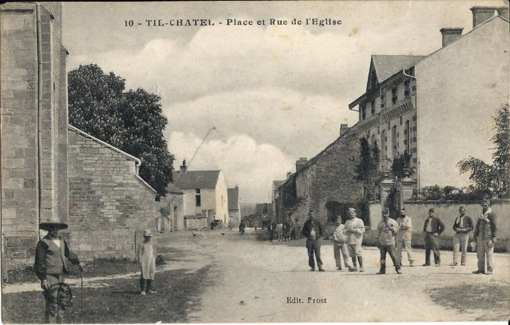 Postcard photo of a street with a church on one side and men standing in the street