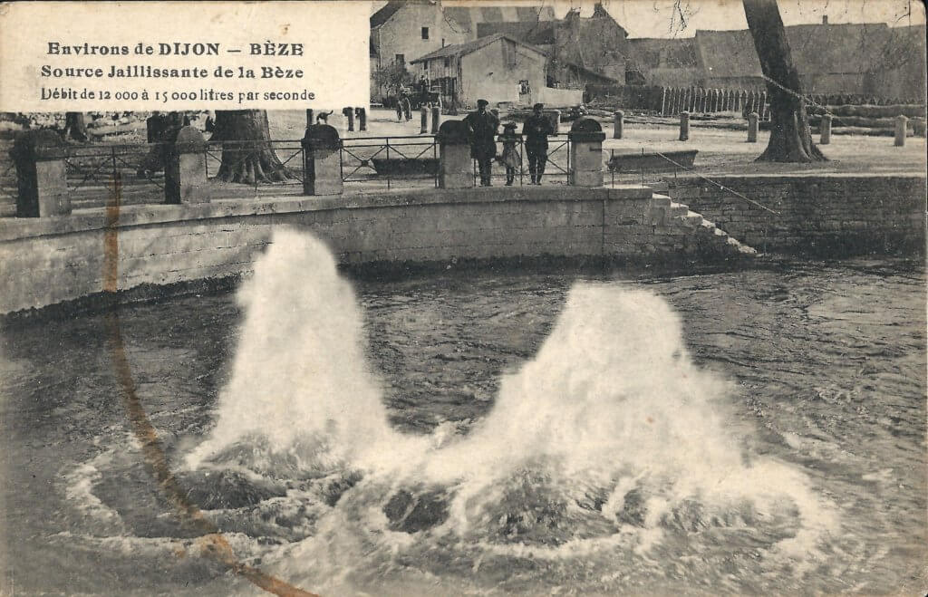 Postcard photo of a spring with two fountain-like jets and an enclosing wall