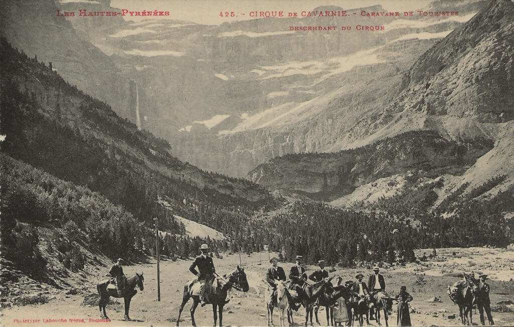 Postcard photo showing tourists and guides on donkeys and horses, with the Cirque de Gavarnie rising behind them.